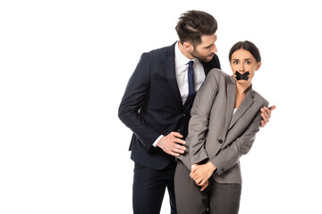 businessman in formal wear touching businesswoman with scotch tape on mouth isolated on white, sexual harassment concept