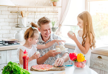 dad with daughters preparing pizza