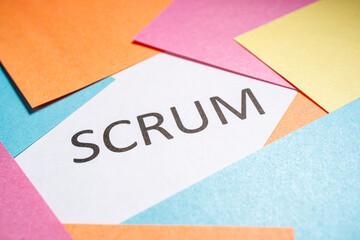 Scrum is written on white paper around which colored papers are located