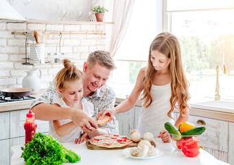 dad with daughters preparing pizza