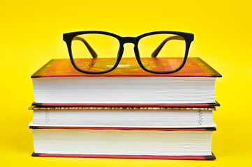 black glasses with books on a yellow background