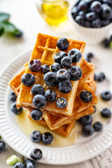 Waffles with fresh blueberries and honey on a white p