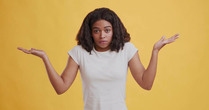 Young black woman shrugging shoulders, raising her hands