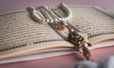 Holy Quran with tasbih or rosary beads. Ramadan concept with pink background