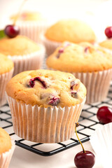 Closeup of homemade muffins with fresh cherry on a baking rack. Homemade cakes, sweet food.