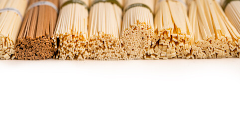 Different noodles lies in a row on a white background, selective focus. Udon, soba and somen...