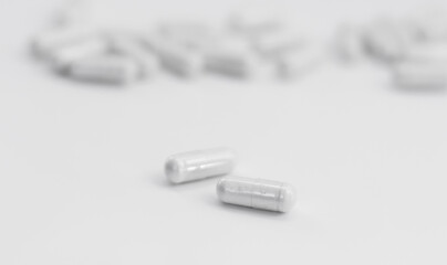 White medicine capsules on white background