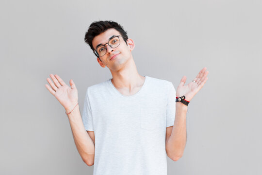 Closeup portrait of dumb clueless young man, arms out asking what's the problem who cares so what, I don't know. Isolated on white background. Negative human emotion, facial expressions, attitude