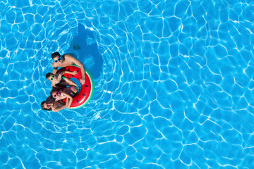 Happy family with inflatable ring in swimming pool, top view. Space for text