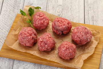 Raw meatball over wooden background