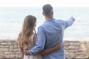 A romantic scene with happy spouses in a loving embrace as they look at the horizon almost at sunset