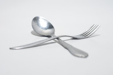 Silver fork sitting across a silver Spoon On White Isolated Background