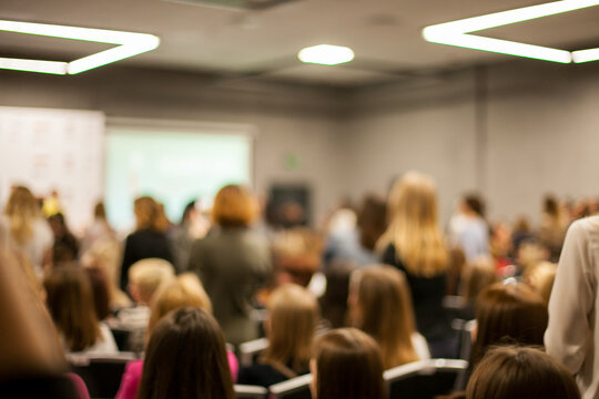 Abstract blurred photo of conference hall or seminar room with speakers on the stage and attendee background, seminar and study concept. Speaker on the podium. People at the conference hall.
