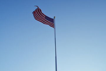 American Flag Waving In Wind Against Clear Blue Sky