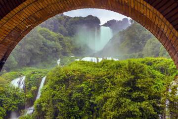 A long exposure view through an arch of the lower walkway of Roman waterfalls at Marmore, Umbria,...