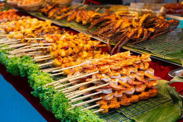 Street food market in Asia. Food counters, mini barbecue on a stick also called satey.
