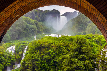 A single exposure view through an arch of the lower walkway of Roman waterfalls at Marmore, Umbria, Italy in summer