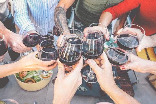 Happy family toasting with red wine glasses at dinner outdoor - People having fun cheering and drinking while dining together - Food and beverage weekend lifestyle activities