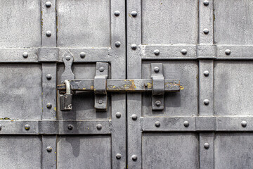 Black, metal doors with rivets and an iron latch