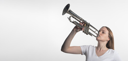 young caucasian woman holding trumpet and playing it isolated on white background. copy space for text © valiantsin