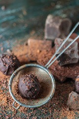 Delicious Chocolate truffles with cocoa powder and dark chocolate on a dark wooden background.