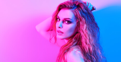Fototapeta premium High Fashion. Woman in colorful neon light, make-up. Sexy girl, stylish wet hair, trendy makeup. Party disco neon style. Creative art beauty portrait, fashionable model face, bright make up