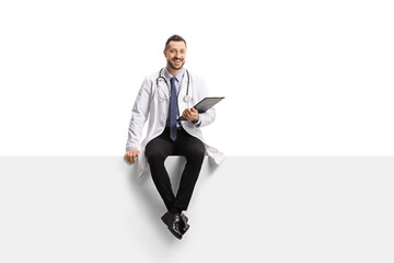 Young male doctor sitting on a blank panel