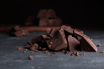 Pieces of tasty dark chocolate on grey table, closeup