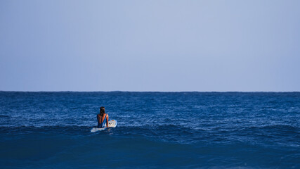 Obraz premium Surfer girl waiting for a wave. Surfer school. Beautiful young woman in swimsuit goes into ocean in hot summer day. Surfer on the wave. beautiful ocean wave. Water sport activity