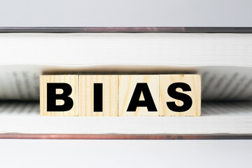 BIAS inscription on wooden blocks in an open book on a white background, copy space