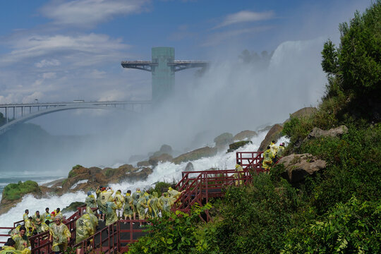 Niagara Falls, NY: Tourists in yellow raincoats enjoy the Cave of the Winds, stairs and platforms at the foot of the American Falls, on Goat Island.