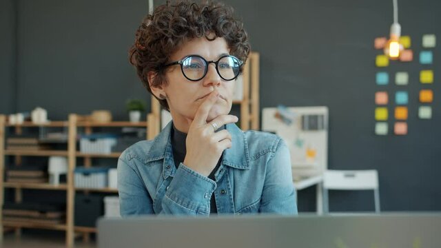 Serious business woman is thinking solving work problem then working with laptop in creative office. Businesspeople, solutions and technology people.