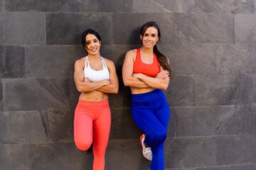 Young Caucasian female friends doing exercises and stretching outside - healthy lifestyle concept