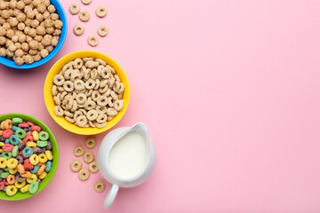 Obraz na płótnie Canvas Corn flakes in bowls with milk in jar on pink background