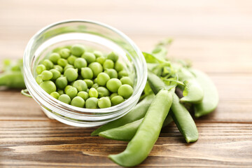 Green peas in bowl on brown wooden table