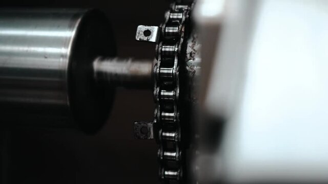 Tracking shot of roller and chain inside printing machine