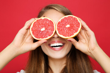 Young girl with fresh grapefruit on red background