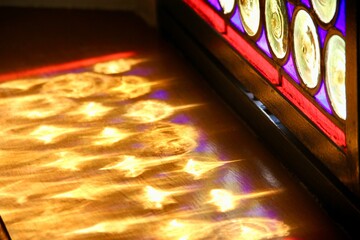 Colorful sunlit stained glass coloring wood in Catholic religious monastery