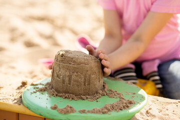 Small cute girl shares a sand castle in a sandbox