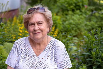 Portrait of a smiling elderly woman, outdoors, in the courtyard.