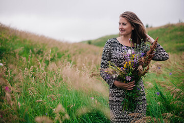 Beautiful, slender girl in a meadow dress with wildflowers