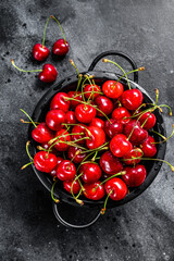 Red ripe cherries in a colander. Black background. Top view.