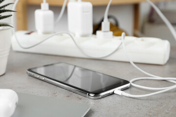 Smartphone charging with cable on light stone table