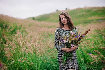 Beautiful, slender girl in a meadow dress with wildflowers