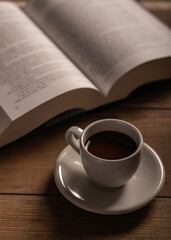 Cup of coffee and a book on a wooden table