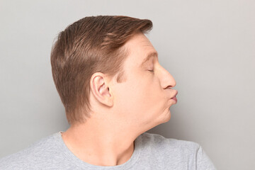 Fototapeta premium Portrait of funny mature man pouting his lips and blowing kiss