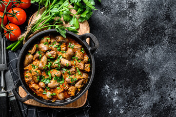 Stew with chicken hearts and vegetables with fresh parsley. Black background. Top view. Copy space