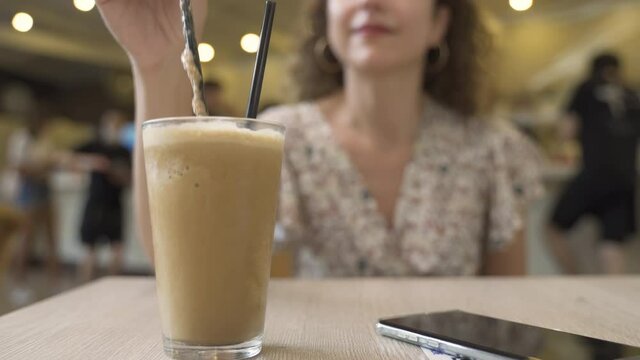 Iced coffee or frappe with woman hand stirring iced. Close-up and selective focus.