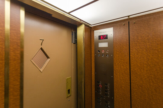 Door closing in old fashioned elevator with wood paneled walls