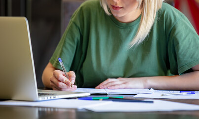 Blonde girl is working with notebook at home as freelancer